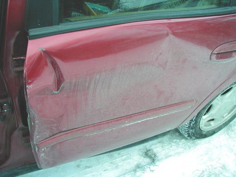 1997 Ford Taurus - This photo shows a heavily damaged red car door, likely from an impact.