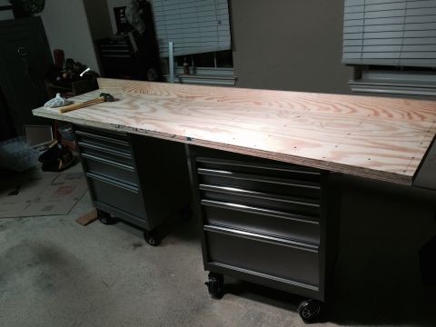 2015 Ford Deluxe - A workbench is set up with a plywood surface atop two dark gray rolling tool chests.