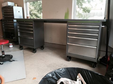 2015 Ford Deluxe - Workbench setup in a garage with tool chests and a stool.