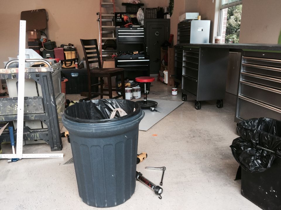 Garage scene with a trash can, tool chests, ladder, and workbenches