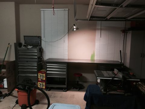 2015 Ford Deluxe - A cluttered garage scene shows a workbench, tool storage, and various workshop equipment.