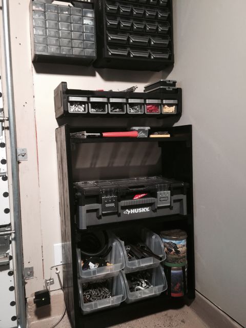 2015 Ford Deluxe - Shelving unit in a garage holds various tools and hardware in plastic bins.