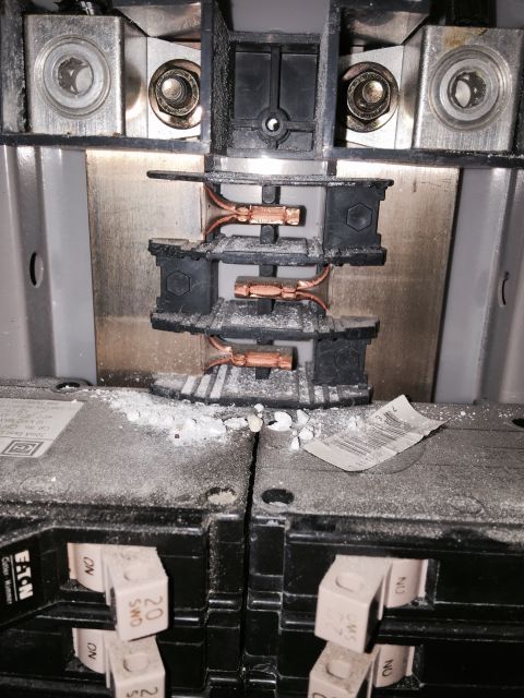 2015 Ford Deluxe - Close-up view of an electrical breaker panel, showing copper connections and circuit breakers coated in dust.