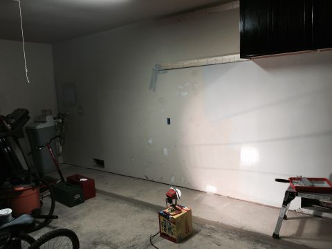 2015 Ford Deluxe - A cluttered garage scene contains various items including exercise equipment, tools, and a portable work light.