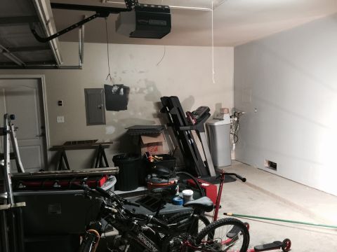 2015 Ford Deluxe - A cluttered garage scene includes a treadmill, water heater, and bicycles, with a garage door opener visible overhead.