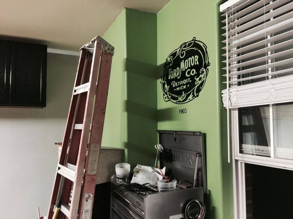 Ford Motor Co. logo on a green wall with a ladder and toolbox