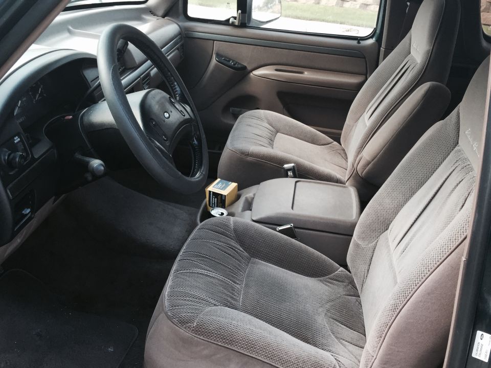 Tan cloth front seats, center console, and black steering wheel inside a Ford Bronco cab