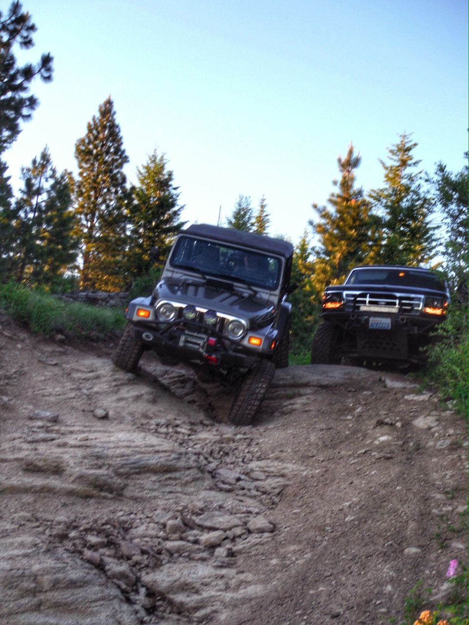Two off-road vehicles climbing a rocky trail.