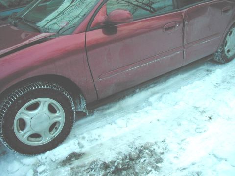 1997 Ford Taurus - Side view of a red 1997 Ford Taurus parked in snowy conditions.