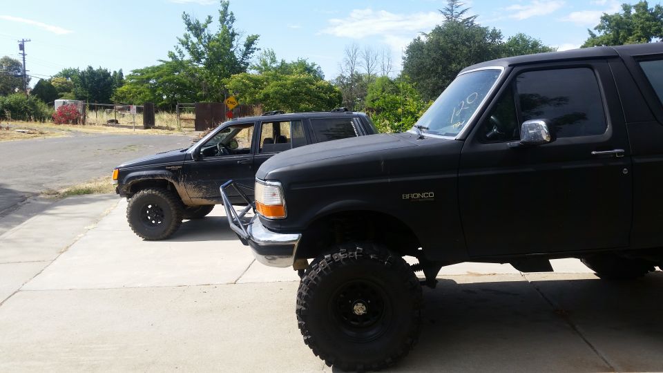 Black Ford Bronco and Jeep Grand Cherokee parked on a concrete driveway.