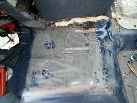 1988 Ford Bronco - The interior floor of a vehicle is shown, with the driver's side floor pan exposed and showing signs of rust and repair. Several bolts and…