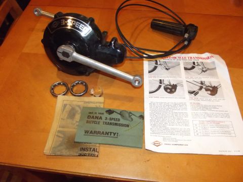 Black 3-speed bicycle transmission with silver crank arm, shifter cable, instructions, and warranty card on a