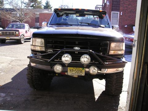 1994 Ford F-150 - A black Ford F-Series truck is parked in front of a garage, with another truck visible in the background.
