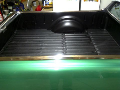 1971 Ford Ranchero - The bed of a green 1971 Ford Ranchero is shown, featuring a black plastic bed liner with ribbed flooring and a chrome trim piece along the…