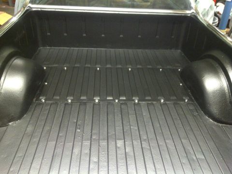 1971 Ford Ranchero - The bed of a classic pickup truck, likely a Ford Ranchero, is shown from a high angle looking forward. The bed has a black spray-in liner w…