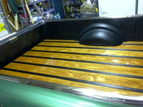 1971 Ford Ranchero - The wooden bed of a pickup truck is shown with black trim strips between the wooden planks. The truck bed is surrounded by black walls and…