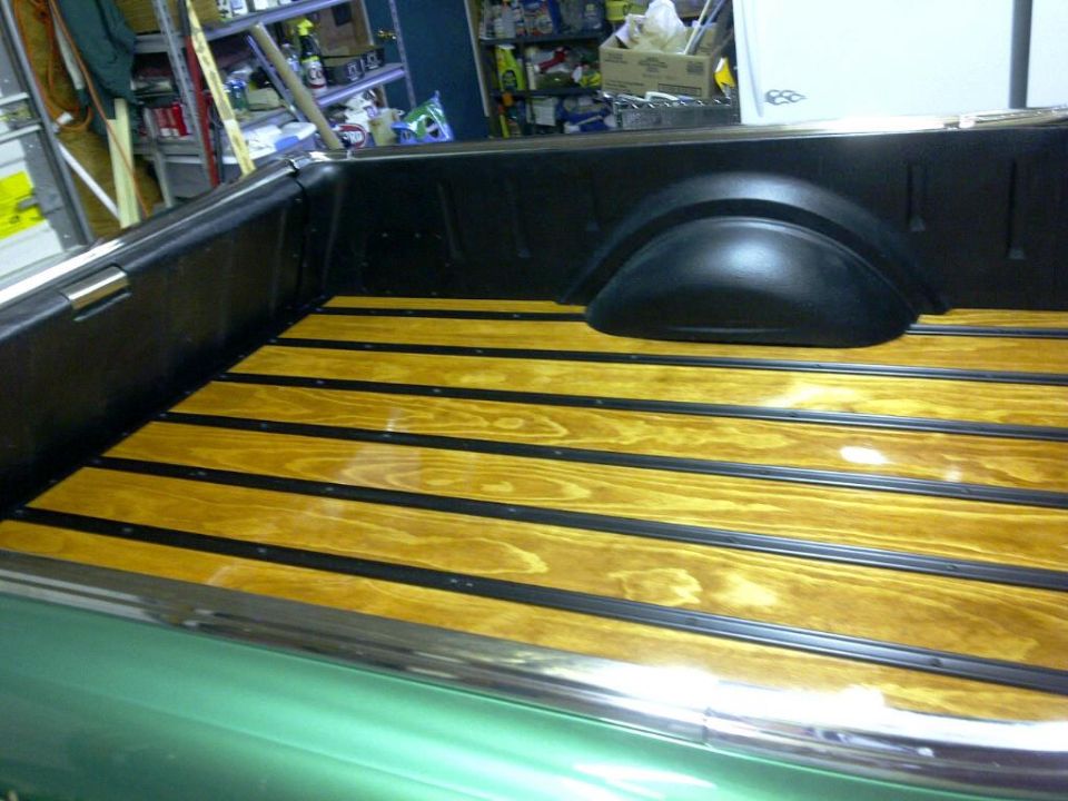 Wooden truck bed with black trim and chrome rail.