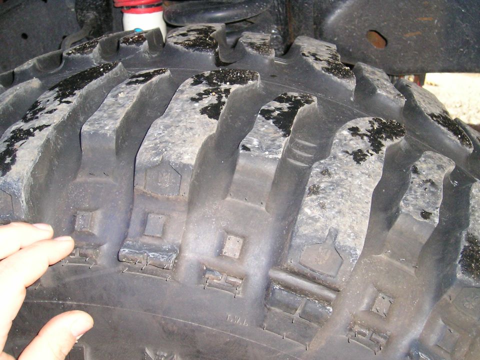 Close-up of aggressive off-road tire tread with mud and debris