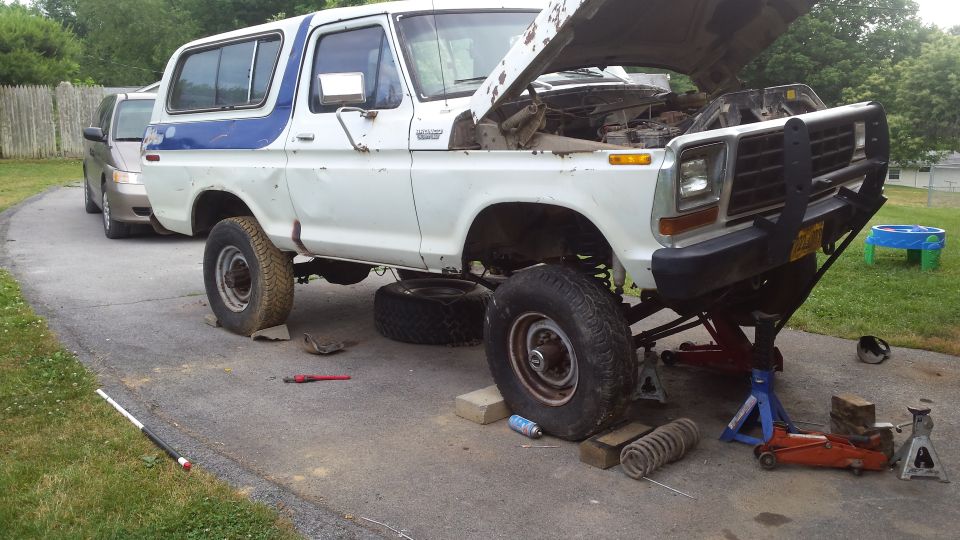 1979 Ford Bronco with hood open, raised on jack stands for maintenance.