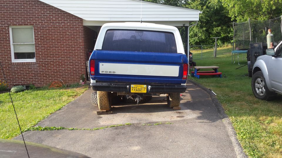 Rear view of a blue and white Ford Bronco on wooden blocks, with a Virginia license plate.