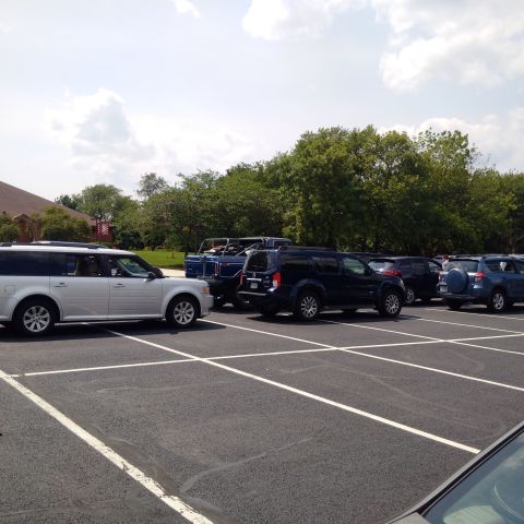 1978 Ford Bronco - A line of SUVs and a blue open-top vehicle are parked in a paved lot on a sunny day. The closest vehicle is a silver SUV.