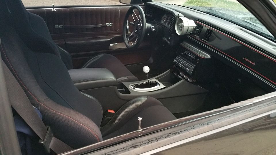 Interior of a modified 1986 Chevrolet Monte Carlo with racing seats and custom shifter.