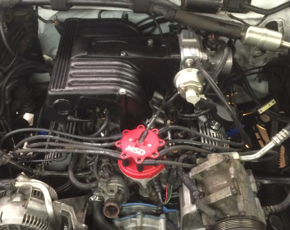 Overhead view of a Ford Bronco engine bay with black intake and red MSD distributor.