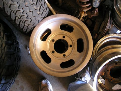 1994 Ford F-150 - A collection of vehicle wheels and tires are piled up in a garage setting.