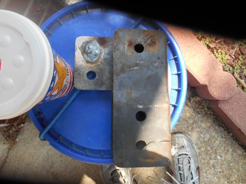 1994 Ford Bronco - A metal bracket with two holes is shown attached to a blue bucket. A white cup with a red, white, and blue design is next to the bracket an…