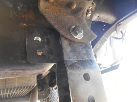1994 Ford Bronco - A close-up view of a custom metal bracket bolted to the frame of a vehicle, likely part of a suspension modification. The bracket is black…