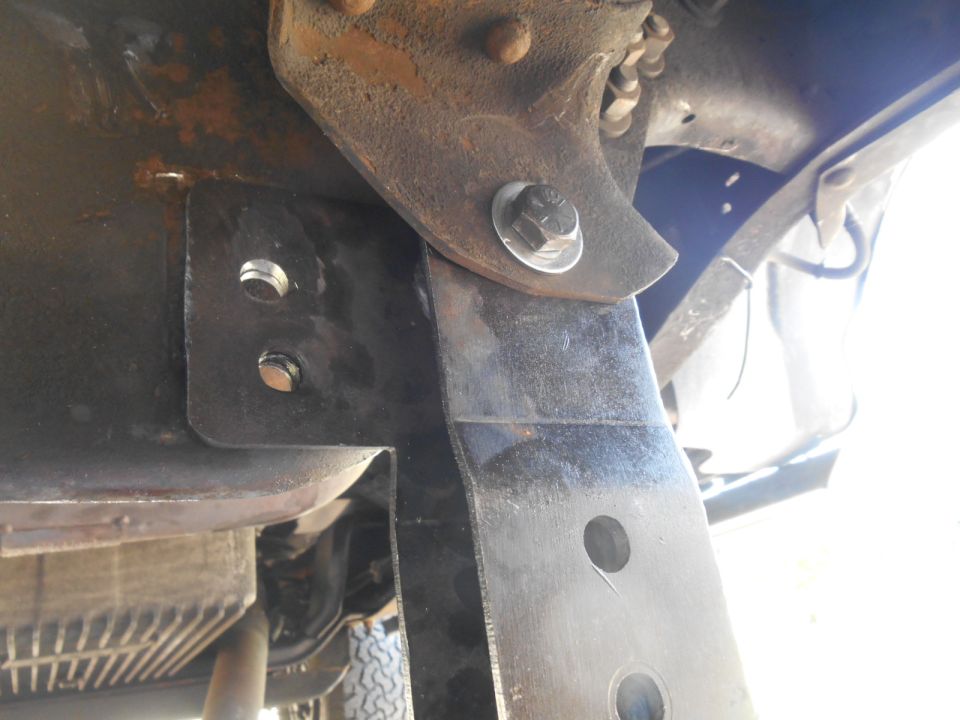 Custom black metal bracket bolted to a vehicle frame.