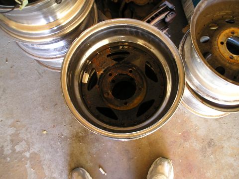 1994 Ford F-150 - Several old, rusty truck wheels are stacked on a concrete floor.