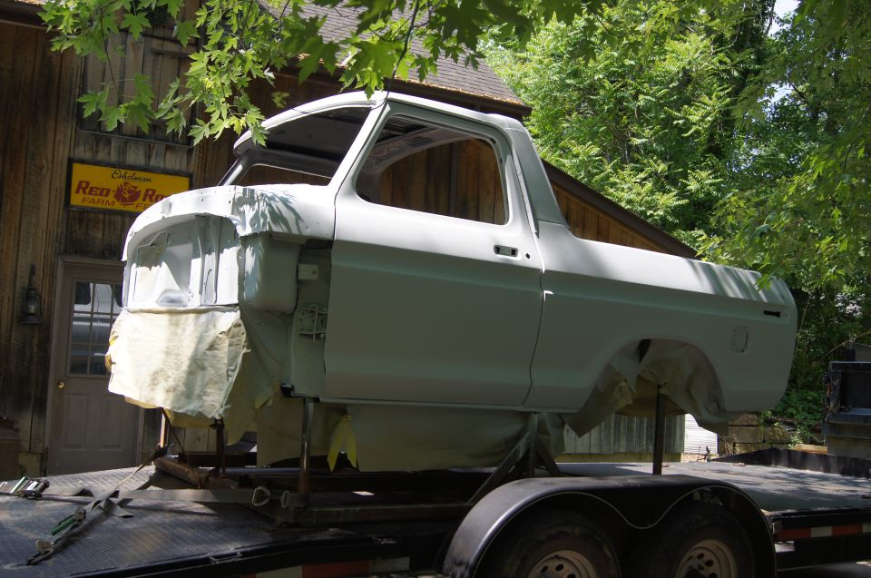 1979 Ford Bronco body on a trailer, primed gray, undergoing restoration.