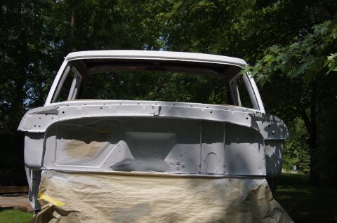 1979 Ford Bronco - The front of a vintage Ford Bronco body, primed in gray, is covered with drop cloths in preparation for painting. The vehicle is outdoors w…