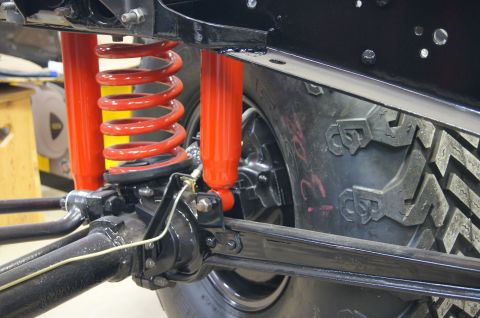 1979 Ford Bronco - A close-up view of the rear suspension system of a vehicle, featuring a red coil spring and a red shock absorber mounted to a black differe…