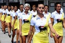 1992 Ford Bronco - A group of women in matching yellow skirts and white shirts with a logo are walking in formation outdoors.
