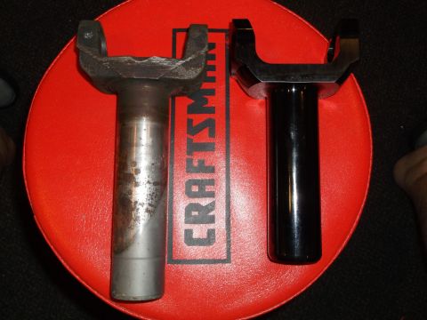 1999 Mercury Grand Marquis - A rusty driveshaft yoke is shown next to a new, black driveshaft yoke on a red Craftsman stool.