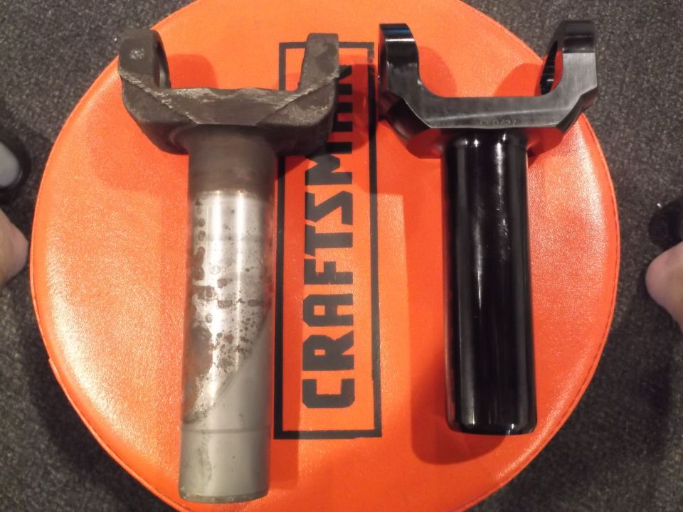 Comparison of an old, rusty driveshaft yoke and a new, black driveshaft yoke.
