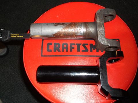 1999 Mercury Grand Marquis - A digital caliper measures the diameter of a metal shaft with a U-joint yoke attached. Below it is a black metal bracket with the text "CKO…