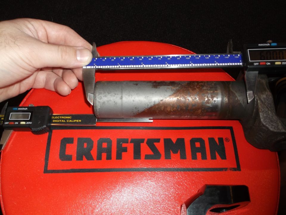 Digital caliper measuring a metal part on a red Craftsman toolbox.