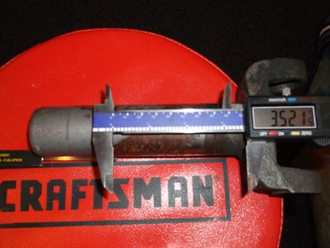 1999 Mercury Grand Marquis - A digital caliper measures the diameter of a cylindrical metal part, showing a reading of 3.52 inches. The part is resting on a red surface…