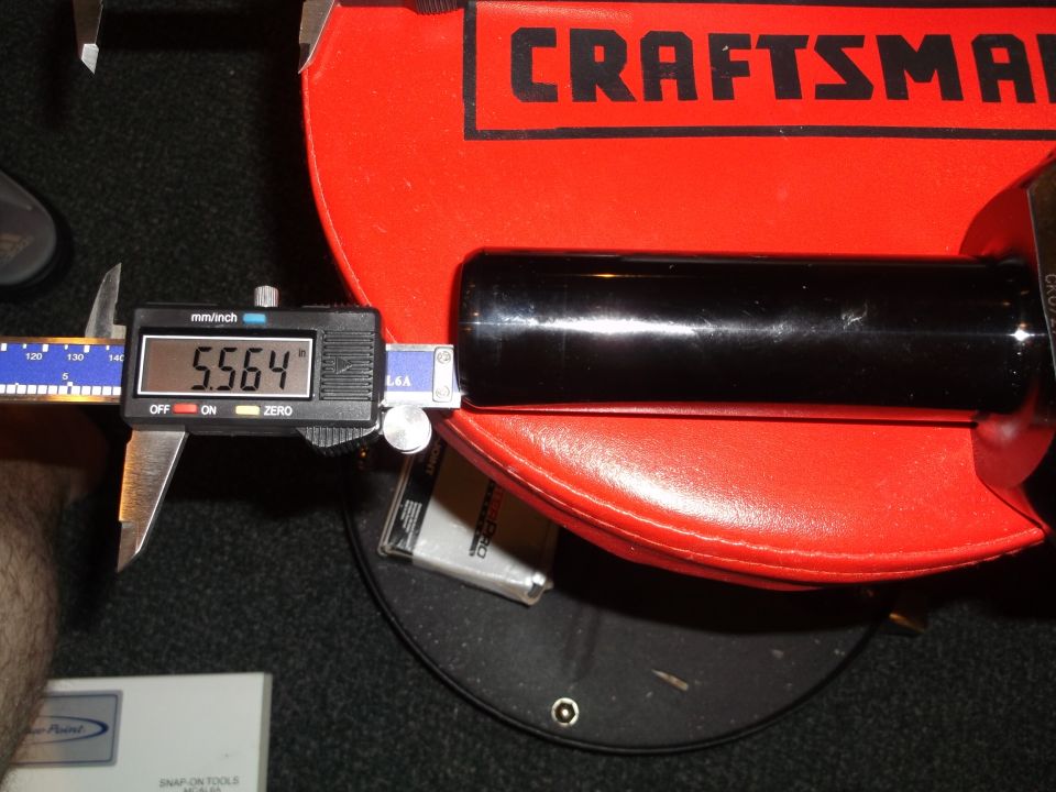 Digital caliper measuring a black cylindrical object at 5.564 inches.