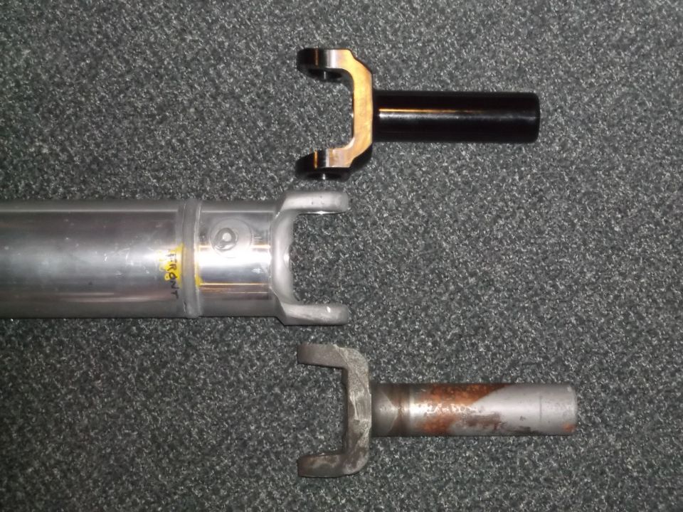 Three driveshaft yokes: one black, one silver with "FRONT" text, and one rusty silver.