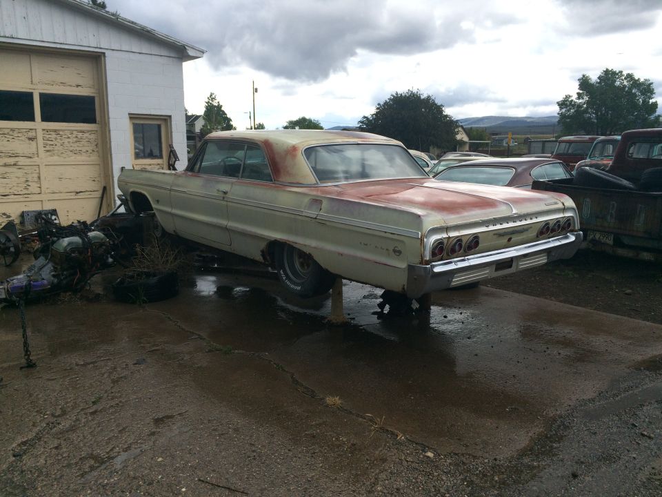 Photo of a 1964 Impala project car parked outside a garage