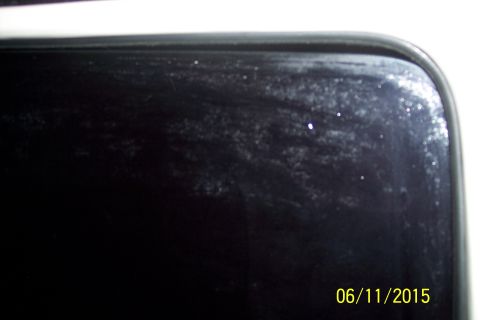 1990 Ford Bronco - A close-up view of the corner of a dark-colored vehicle with a reflective surface, showing some smudges and small bright spots. The date "0…