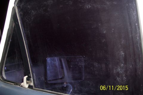 1990 Ford Bronco - A close-up view of the dusty rear passenger window of a vehicle, showing a side mirror reflected in the glass. A date stamp of "06/11/2015"…