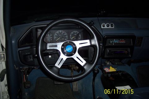 1990 Ford Bronco - The interior of a Ford Bronco shows a custom steering wheel with a Ford logo, aftermarket gauges, and a manual transmission shifter. The da…