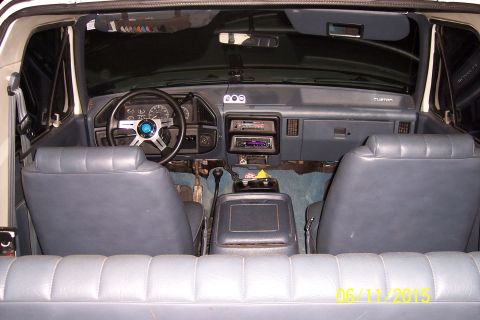 1990 Ford Bronco - The interior of a vintage Ford Bronco is shown, featuring blue cloth seats, a custom steering wheel, and an aftermarket stereo system. The…