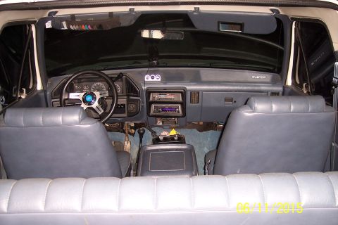 1990 Ford Bronco - The interior of a 1990 Ford Bronco shows the dashboard, steering wheel, and front seats. The vehicle has a blue interior with a custom stee…