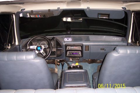 1990 Ford Bronco - The interior of a 1990 Ford Bronco is shown, featuring blue vinyl seats, a custom steering wheel, and aftermarket audio equipment. The dash…